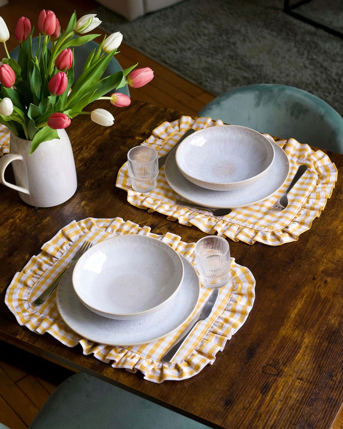 Set de table à carreaux vichy jaune et blanc, en coton 100 % avec finition matelassée et volant sur tout le contour. Fabriqué à la main à Biarritz, il apporte une touche raffinée et chaleureuse à une table joliment dressée.