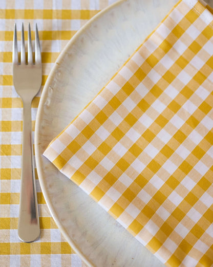 Zoom sur la serviettes de table en coton 100 %, à motif vichy jaune et blanc. Le design classique et intemporel du vichy apporte une touche de fraîcheur et de gaieté à votre table, tout en mettant en valeur la qualité et l’élégance de chaque détail. Fabriquées à la main à Biarritz, elles sont idéales pour sublimer vos repas avec style.