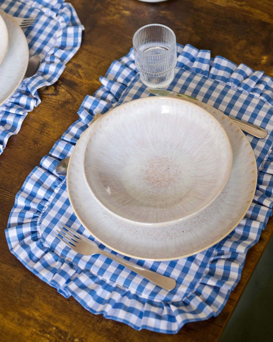Set de table à carreaux vichy bleu et blanc, en coton 100 %, avec finition matelassée et volant tout autour. Confectionné à la main à Biarritz, il apporte une touche élégante et chaleureuse à une table joliment dressée.